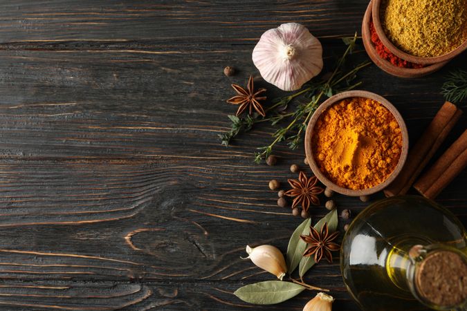 Wooden table scattered with spices and ingredients for cooking, copy space