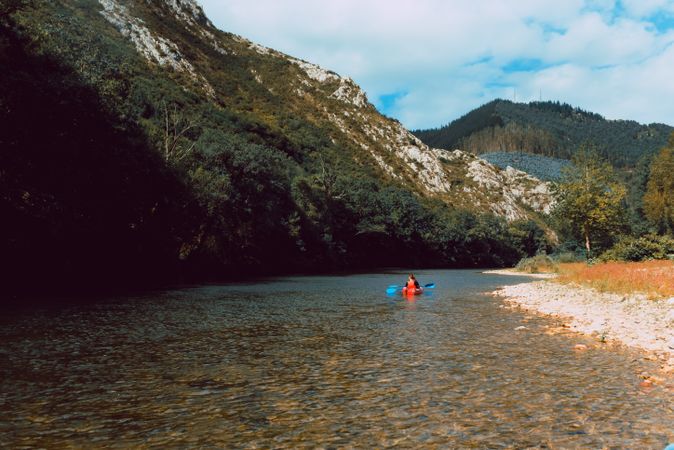 Female kayaking with paddle in raised hands