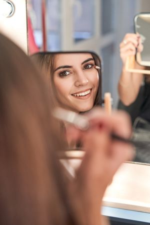 Content woman applying makeup in studio