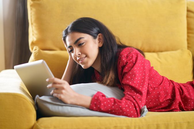 Woman relaxing at home while reading on a tablet