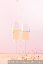 Two glasses of champagne and falling confetti stars on pink background 5qZdY4