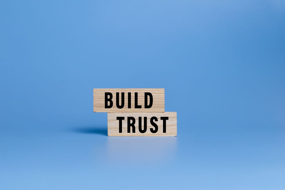 male hand putting wooden blocks with build trust words isolated on blue background