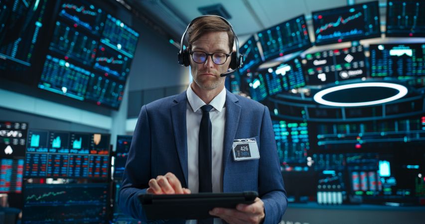Portrait of a Stock Exchange Broker Using Tablet Computer, Researching Real-Time Stocks Data, Analyzing Commodities and Exchange Market Charts.
