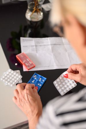 Crop unrecognizable female sorting pills in pill containter