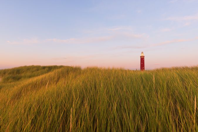 Red lighthouse from afar on green grass field