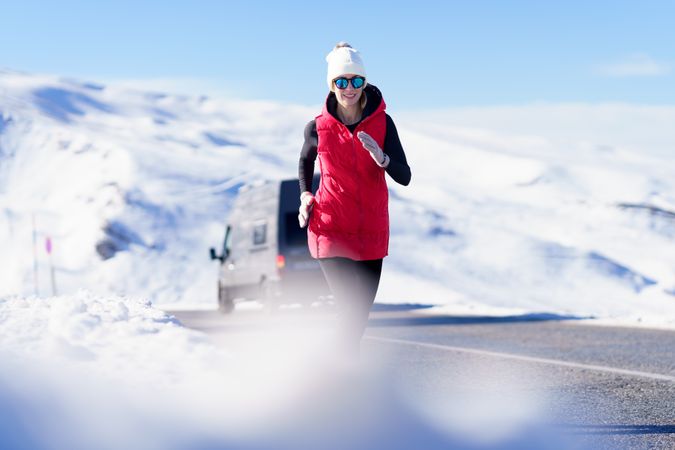 Woman in winter wear jogging on mountain road