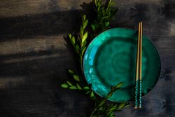 Asian table setting with chopsticks & cherry blossom on teal plate