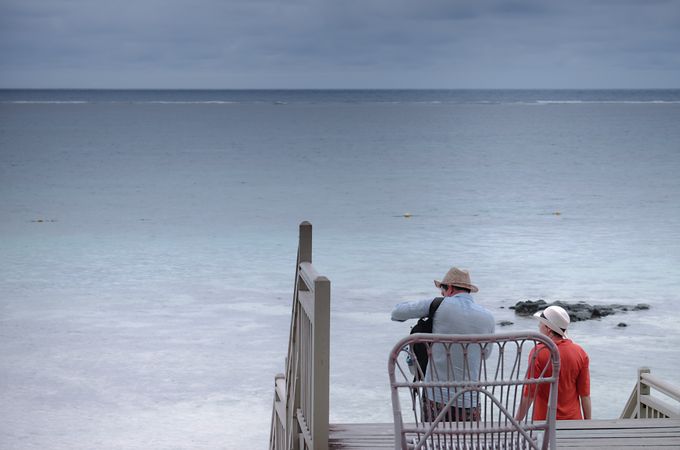 Two tourists in sun hats walking down to the Indian Ocean