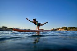 Concentrated woman practicing yoga on paddleboard