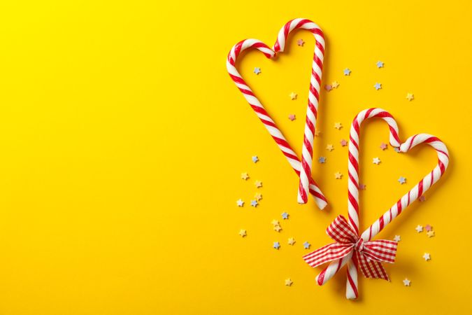 Composition with sweet candy canes on color background, space for text