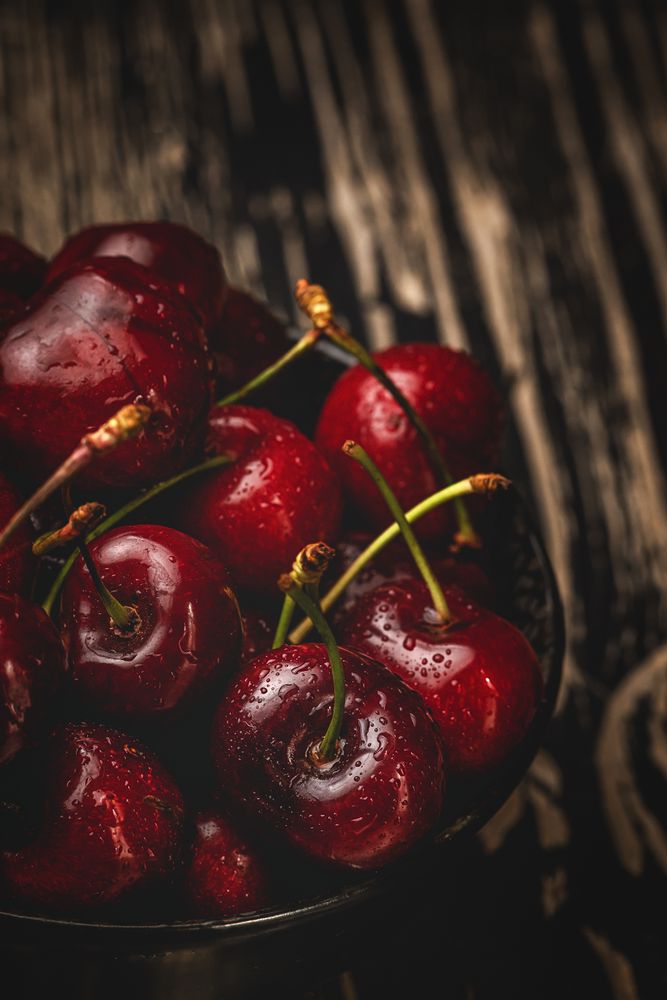 Juicy red cherry in bowl on rustic surface
