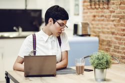 Woman in loft apartment working on computer at table