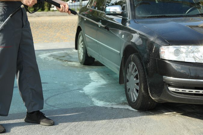 A man washes a car in a manual car wash. Clear car