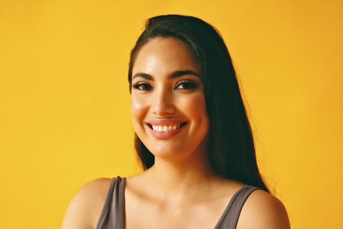 Smiling Hispanic woman looking at camera in yellow room