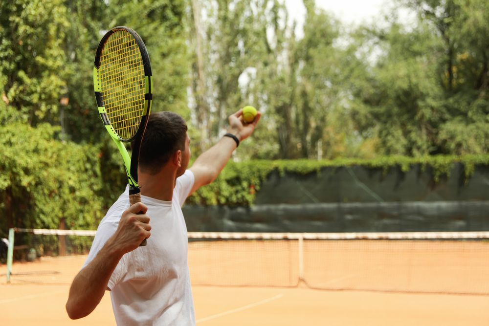 Young man in white t-shirt serve the tennis ball