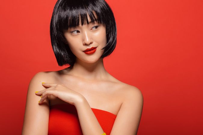 Stylish female model wearing wig against red background