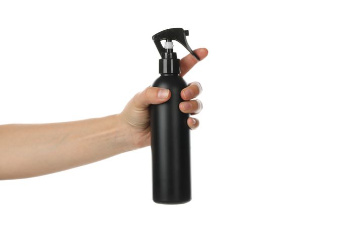 Female hand holds hairdressing spray, isolated on plain background