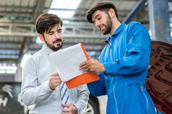 Mechanic explaining repairs to customer on clipboard
