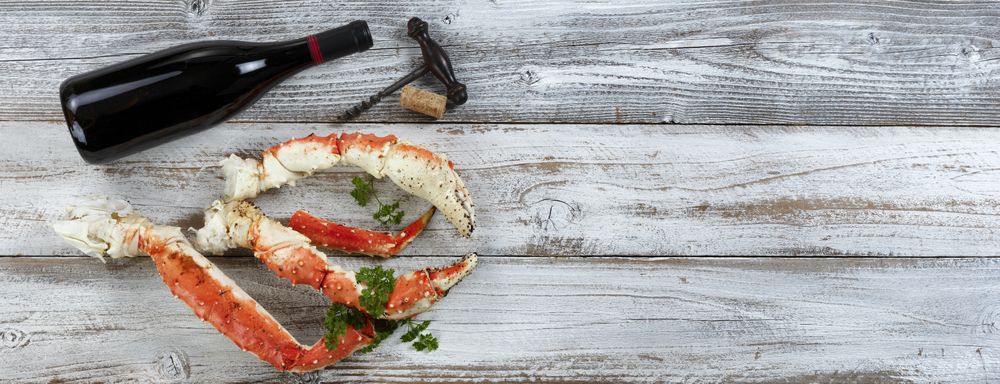 King crab claws and wine bottle on rustic wood in flat lay format