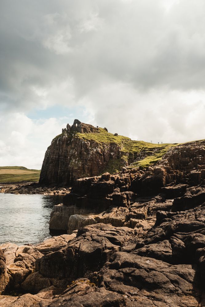 Rocky coast among tranquil ocean water in sunny day
