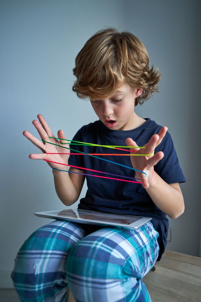Astonished boy playing string game with tablet