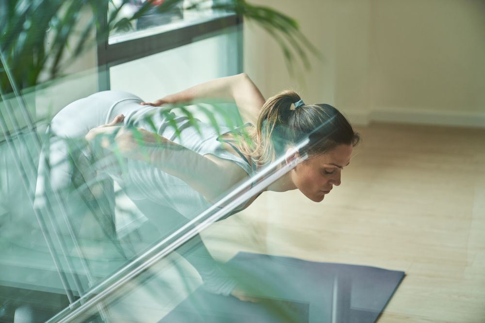 Woman in activewear taking Prasarita Padottasana B pose during yoga session