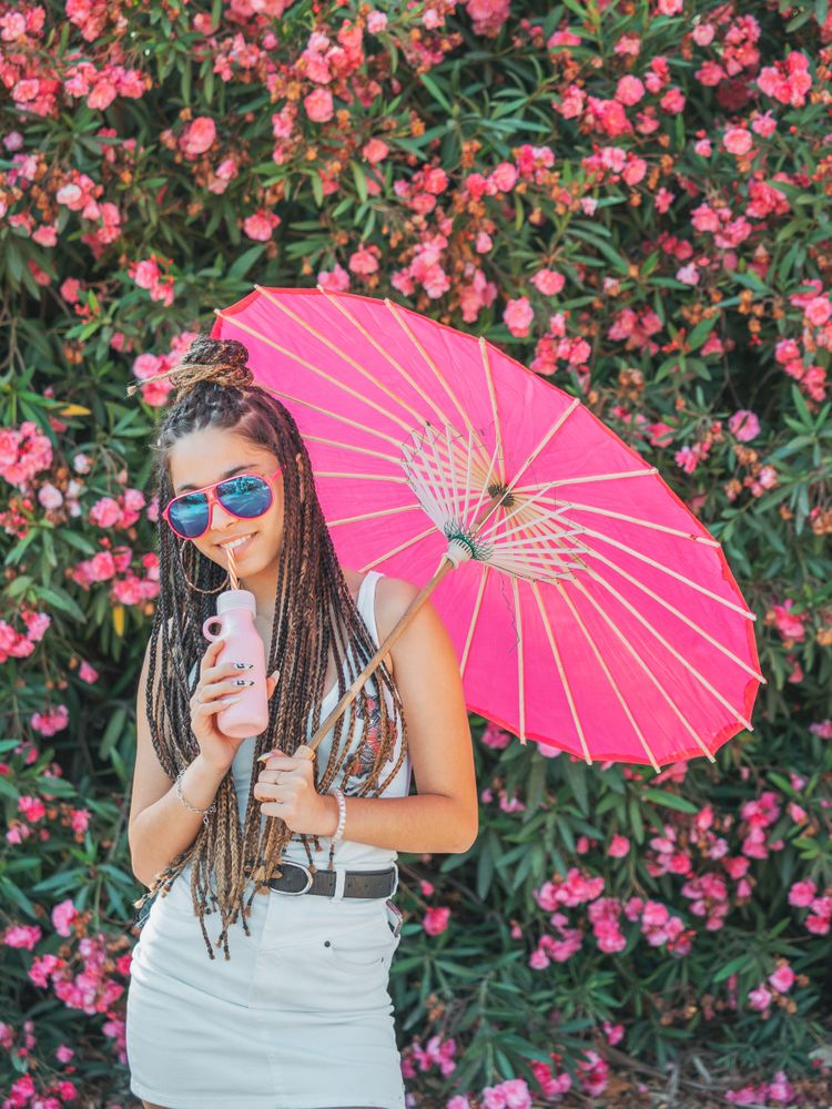 Female with umbrella standing near blooming trees