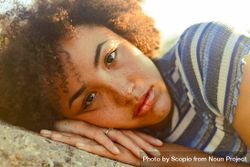 Woman with freckles and curly hair laying on rock bed9E4