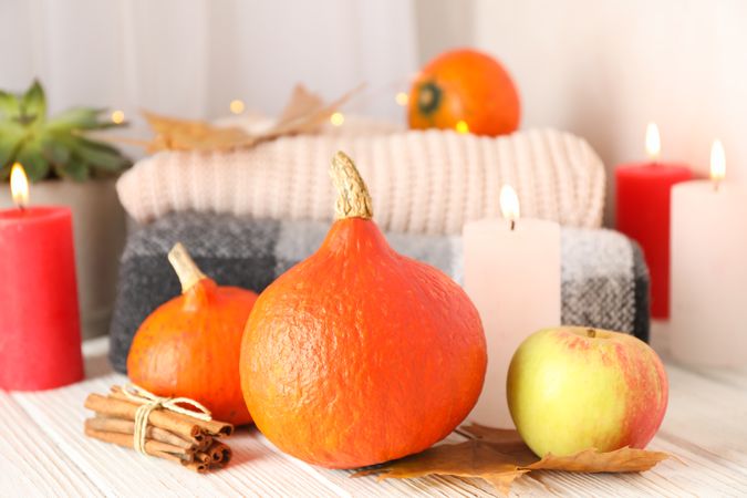 Pumpkins, clothes, leaves and candles on wooden background, copy space