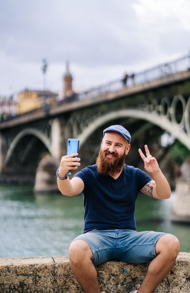 Satisfied male tourist taking selfie on smartphone at quay