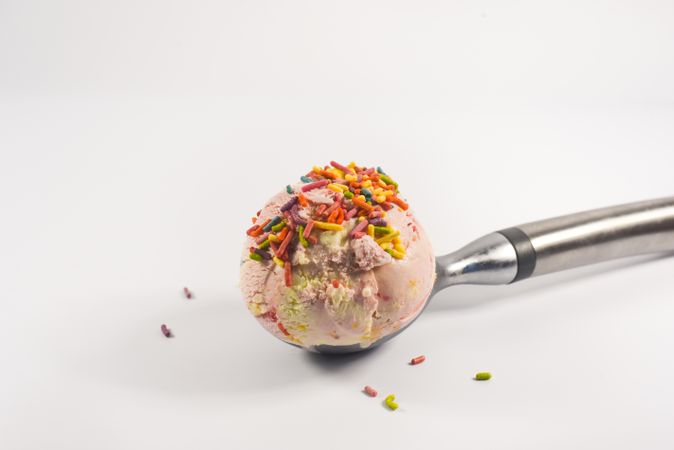Pink ice cream scoop with sprinkles on table