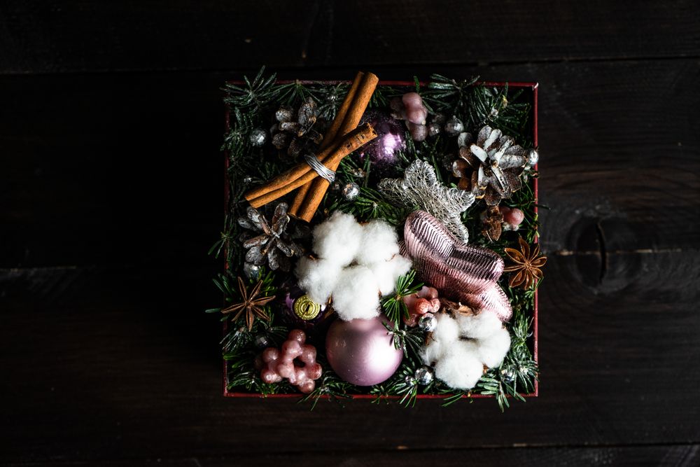 Top view of box of Christmas ornaments with cinnamon, fir, baubles and pinecones