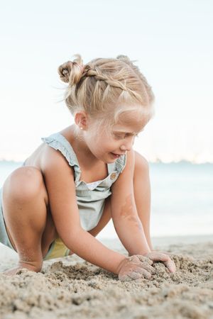 Cute girl playing with sand on beach