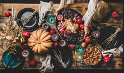 Thanksgiving party table setting for gathering with woman serving roast chicken