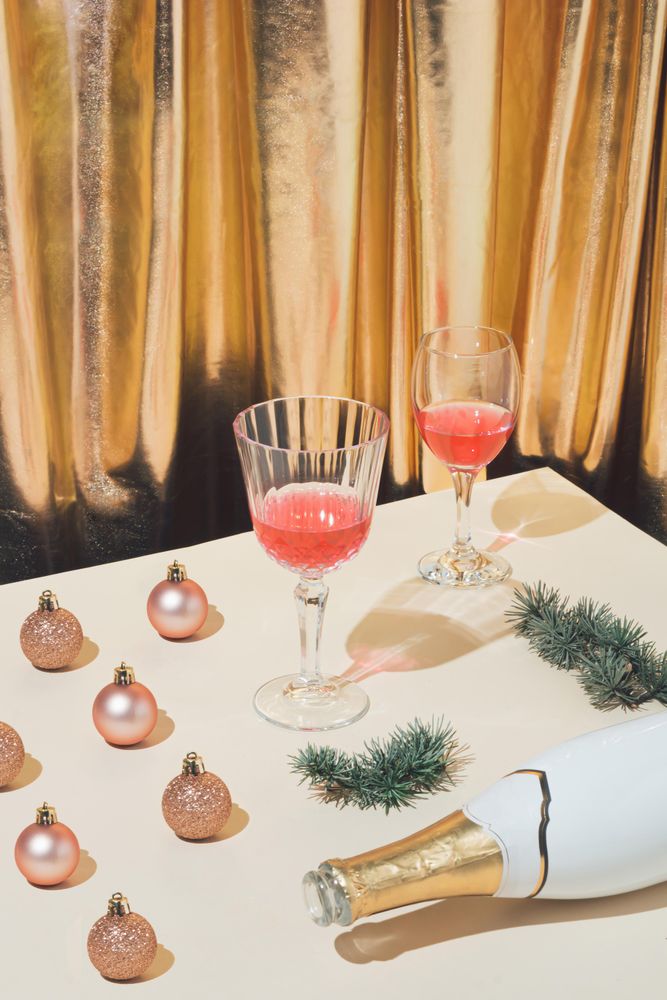 Table with festive decorations, champagne and glasses against a gold curtain