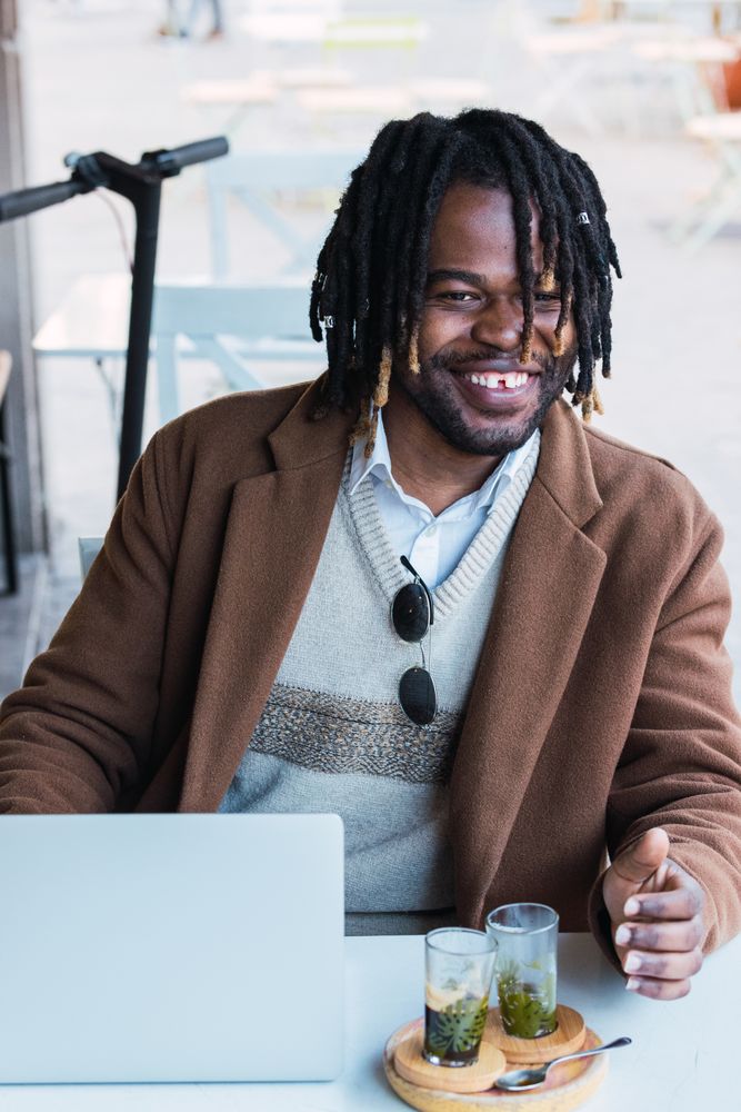 Serious Black man with espresso and glass of water in cafe