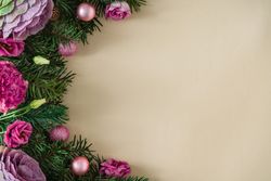 Top view flat lay of fir leaves and pink flower with tan copy space