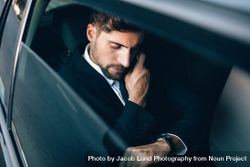White business executive checking time and making phone call in car benAl0