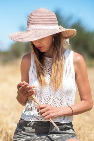 Crop woman with cereal grass in meadow