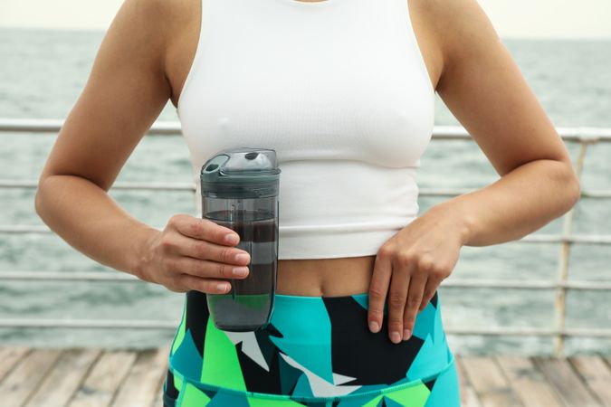 Young woman with bottle of water in hands at sea, close up