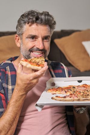 Happy man eating pizza at home