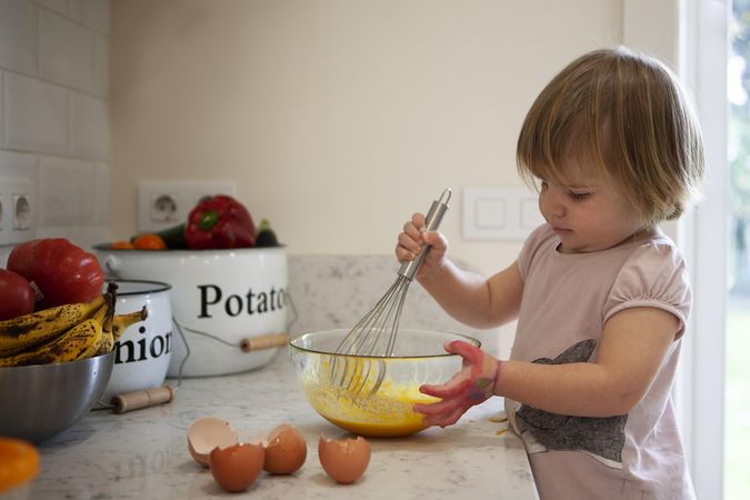 Girl mixing eggs in kitchen