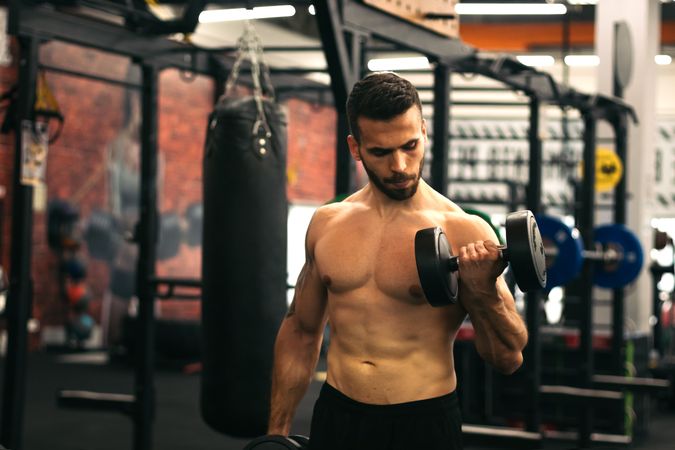strong man training arms in front of the mirror in a gym