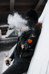 Woman in mask and jacket smoking on street