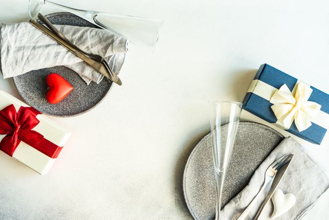 Top view of two grey plates with champagne flutes and gifts