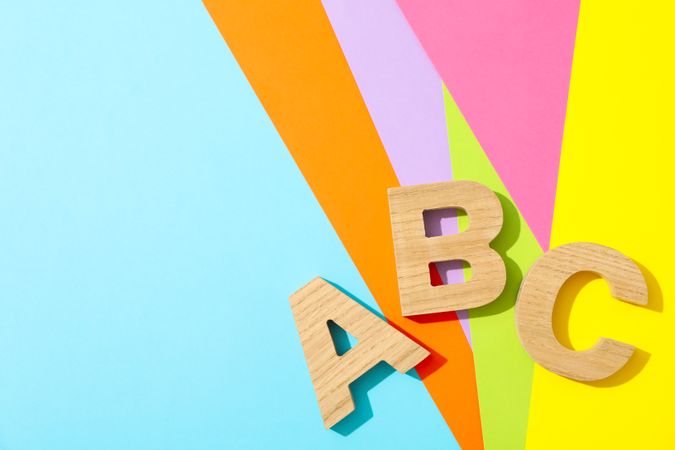 Letters ABC lined with wooden letters on multicolor background