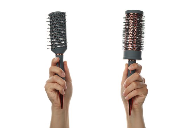 Female hands hold hair brushes, isolated on blank background