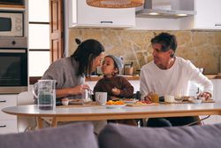 Smiling mother in moment of kiss with son during breakfast