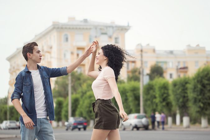 A teenage boy and a girl are dancing in the street