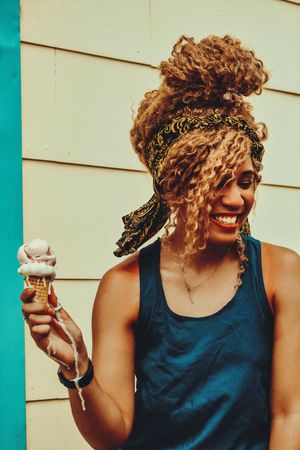Happy Black female enjoying an ice cream cone in the sun, vertical